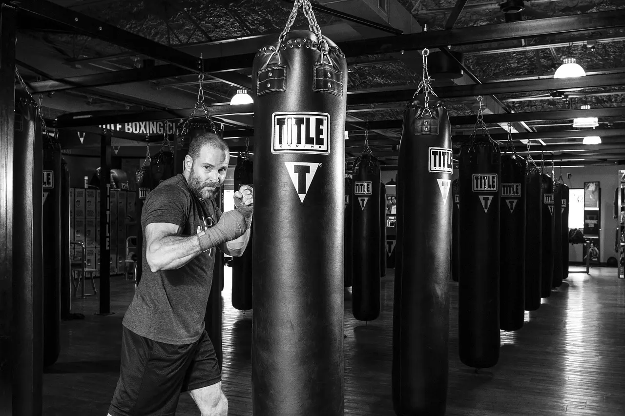 Mand der træner med sandsæk i boksegym